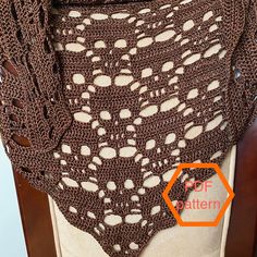 a crocheted shawl is shown on a mannequin with an orange tag