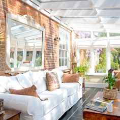 a living room filled with white furniture and lots of windows covered in sun shining through