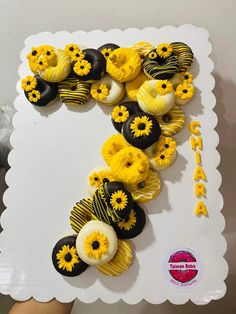 a white plate topped with yellow and black cupcakes next to a cake shaped like the letter f