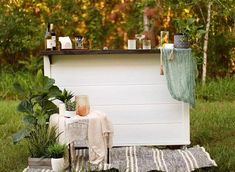 an outdoor bar set up with potted plants and wine bottles on the top shelf