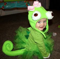 a baby in a green frog costume sitting on the floor