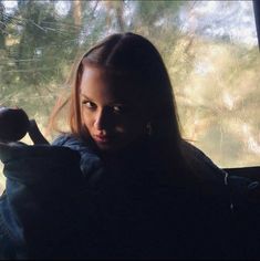 a woman sitting in front of a window holding an apple