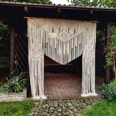 a white macrame hanging from the side of a wooden structure in a garden