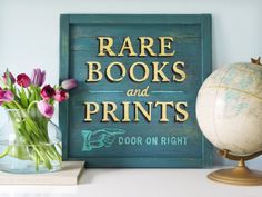 there is a vase with flowers on the table next to a sign that says rare books and prints