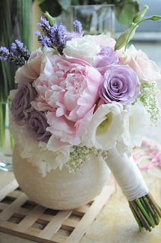 a bouquet of flowers sitting in a vase on top of a wooden table next to another vase