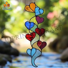 a stained glass wind chime hanging in the shape of hearts with water running through it