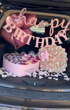 two heart shaped cakes in the trunk of a car with balloons and confetti