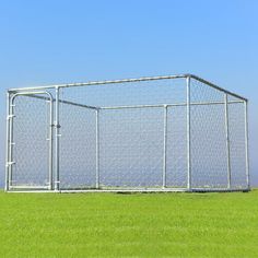 a large chain link fence in the middle of a field with green grass and blue sky