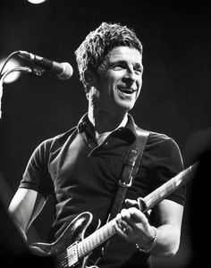 black and white photograph of a man playing an electric guitar in front of a microphone