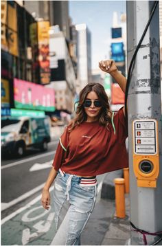 a woman leaning against a pole in the city