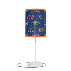 a lampshade with an orange base and blue fabric shade that has monster trucks on it