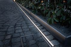 a long metal planter sitting on top of a cobblestone road