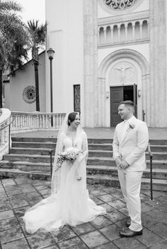 a bride and groom standing in front of a church with steps leading up to it