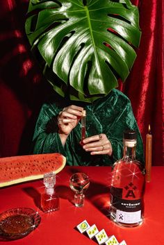 a woman sitting at a table next to a large green leaf