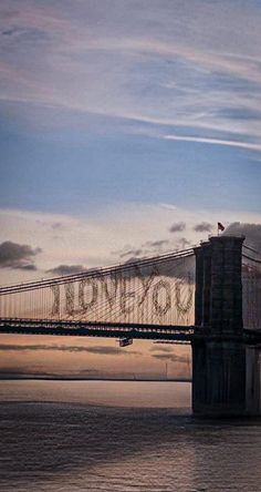 an image of a bridge that is going over the water at sunset or dawn with clouds in the sky