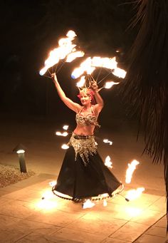 a woman in a belly dance outfit holding fire torches