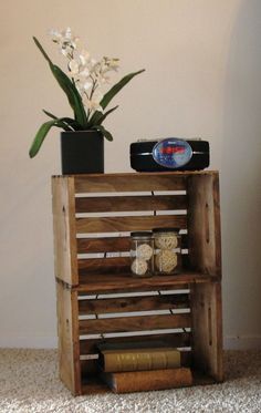 a wooden crate with some books and jars on it next to a flower pot filled with flowers