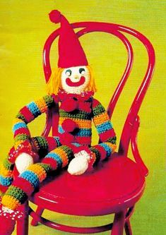 a knitted clown sitting on top of a red chair