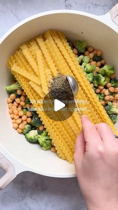 someone is mixing pasta with broccoli and chickpeas