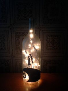 a bottle with some lights in it and a person standing on top of the bottle