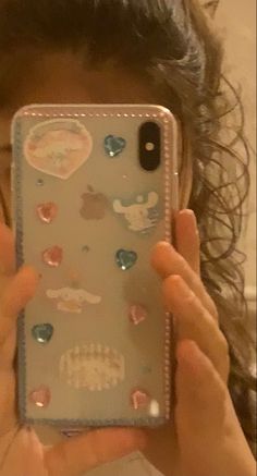 a woman holding up her cell phone to take a selfie with the case covered in stickers