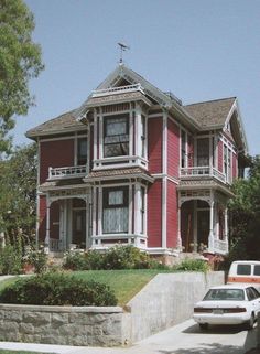 a car parked in front of a red house with white trim on the windows and balconies