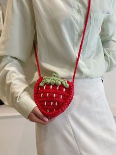 a woman wearing a white shirt is holding a red purse with a strawberry on it