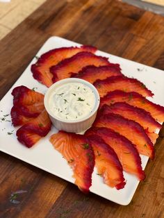 there is a white plate topped with bacon strips and dip on the side, along with other appetizers