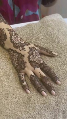 a woman's hand with henna on top of her arm and hands in the middle