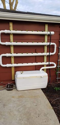 a white water heater sitting on top of a sidewalk next to a red building