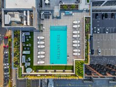 an aerial view of a swimming pool in the middle of a building with lounge chairs around it