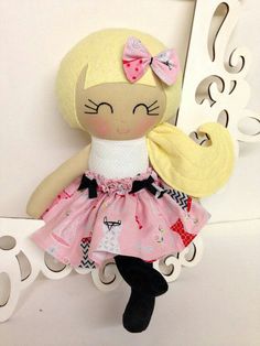 a doll with blonde hair wearing a pink dress and black shoes sitting on a shelf