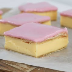 several pieces of cake sitting on top of a piece of wax paper with pink icing