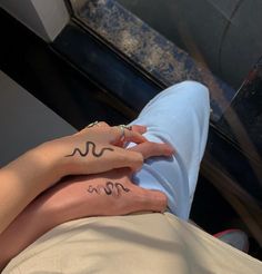 two people with matching tattoos on their hands, one holding the other's hand