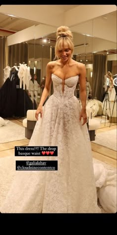 a woman standing in front of a mirror wearing a wedding dress