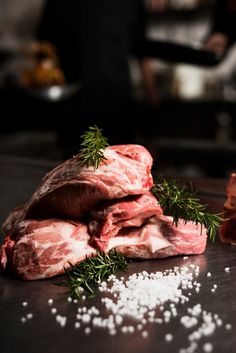 some raw meat sitting on top of a table next to salt and pepper flakes