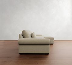 a couch sitting on top of a hard wood floor next to a wall with white walls