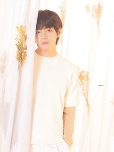 a young man standing next to a white curtain