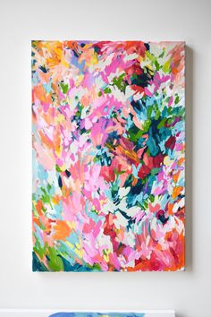 an abstract painting hangs on the wall next to a blue and white vase with flowers in it