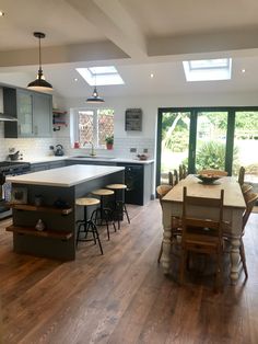 an open kitchen and dining area with wood flooring in the center, large glass doors leading outside