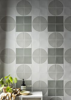 a white table with a potted plant on it next to a gray tiled wall