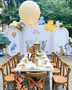 a table set up with winnie the pooh balloons and decorations for a birthday party