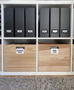 three wooden boxes with labels on them sitting in front of a bookcase filled with files