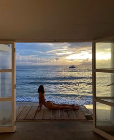 a woman is sitting on a deck looking out at the ocean