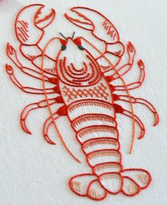 a red embroidered lobster sitting on top of a white surface