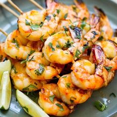 shrimp skewers with lime wedges on a plate