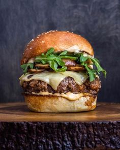 a cheeseburger with meat, lettuce and sauce on a wooden board