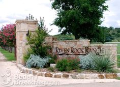 the entrance sign to river rock ranch is surrounded by flowers and plants in front of it