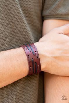 a close up of a person wearing a brown leather bracelet with black stitching on it