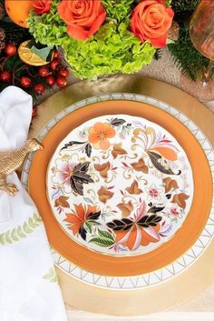 an orange and white plate sitting on top of a table next to some green flowers